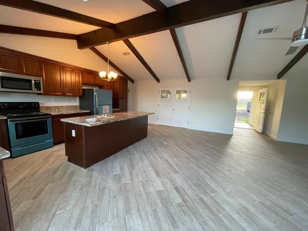 a view of an empty room with wooden floor and a ceiling fan