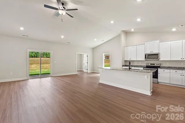 a view of kitchen with stainless steel appliances refrigerator stove and wooden floor
