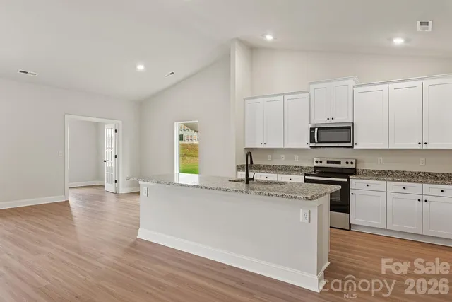 a large kitchen with stainless steel appliances granite countertop a stove a sink dishwasher and a refrigerator