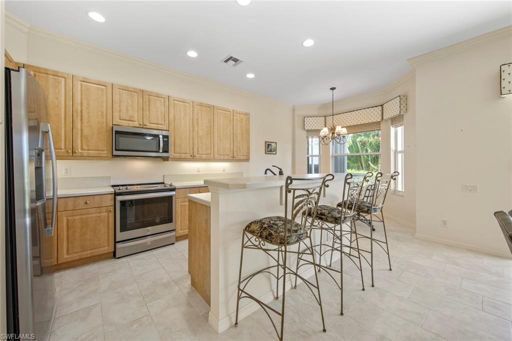 9097 Springview Loop Estero, FL 33928 - Photo 18 of 50 a kitchen with stainless steel appliances granite countertop a stove top oven a sink dishwasher a dining table and chairs with wooden floor