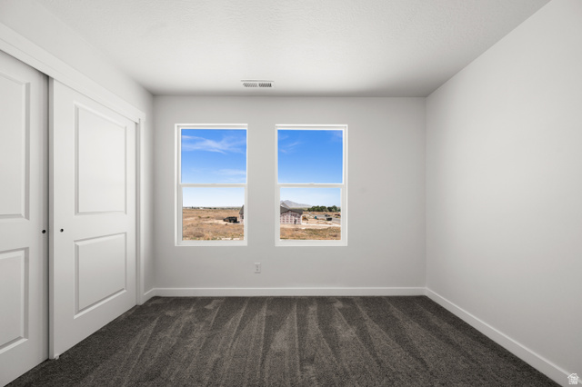 1554 Pheasant Road Eagle Mountain, UT 84005 - Photo 25 of 29 Unfurnished bedroom with dark carpet and a closet