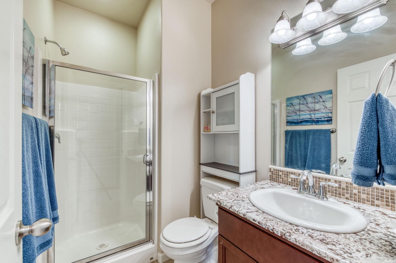 3610 Griffith Avenue Clovis, CA 93619 - Photo 16 of 22 a bathroom with a granite countertop sink toilet a mirror a vanity and shower