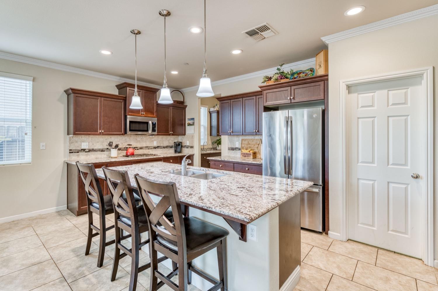 3610 Griffith Avenue Clovis, CA 93619 - Photo 6 of 22 a kitchen with stainless steel appliances kitchen island granite countertop a refrigerator a stove a sink and a oven