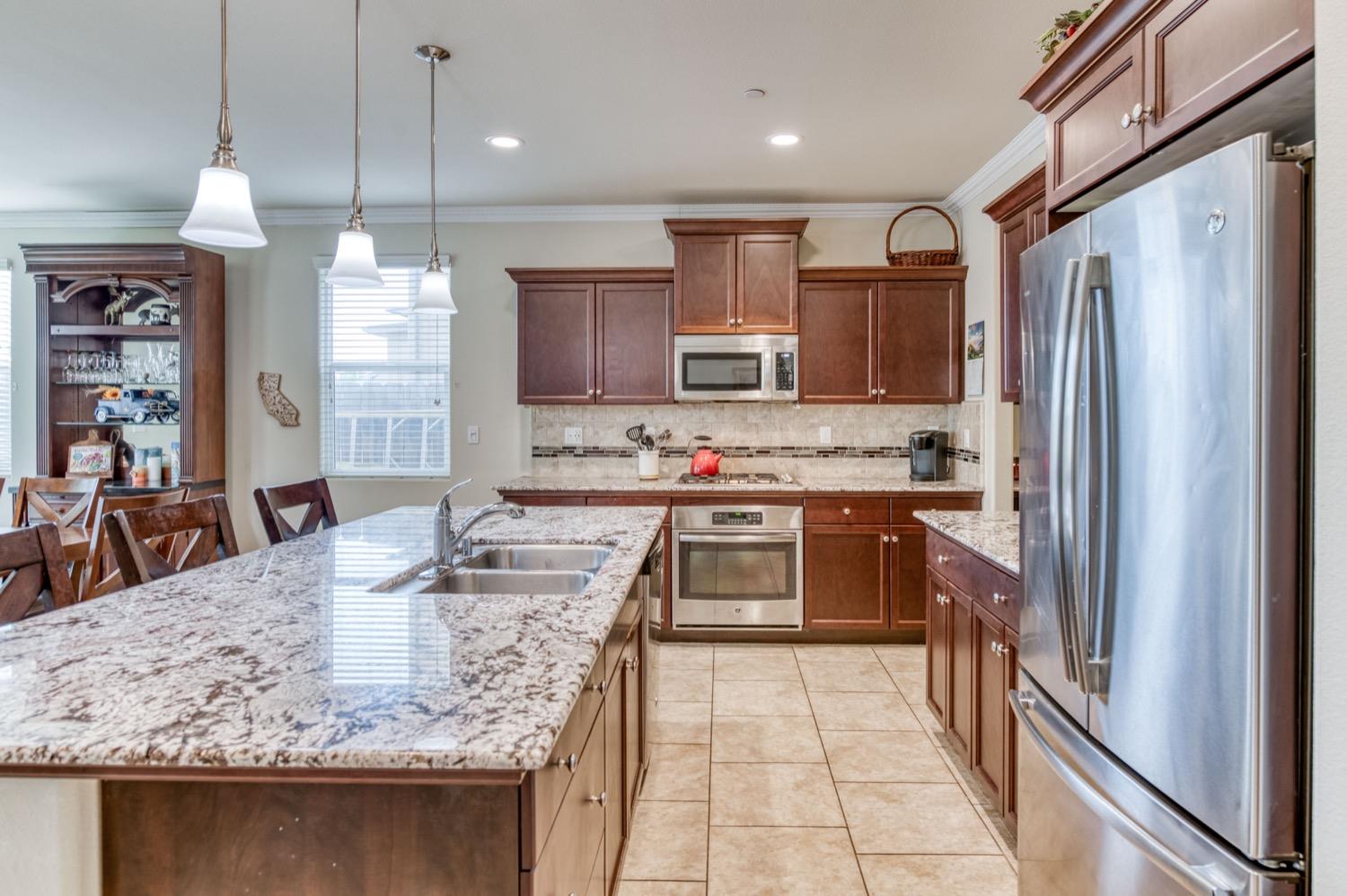 3610 Griffith Avenue Clovis, CA 93619 - Photo 7 of 22 a kitchen with stainless steel appliances granite countertop a sink refrigerator and cabinets