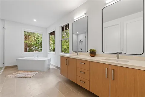 a bathroom with double vanity sinks a large mirror and a bathtub