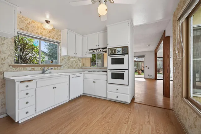 a kitchen with stainless steel appliances a stove a sink and white cabinets with wooden floor