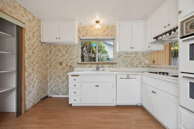 a kitchen with granite countertop a sink cabinets stainless steel appliances and a window