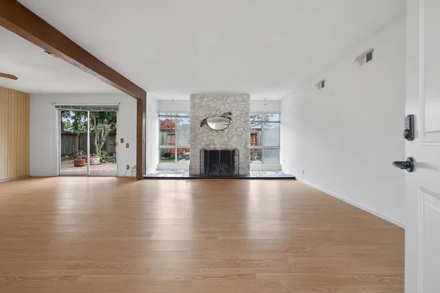 an empty room with floor to ceiling windows and fireplace