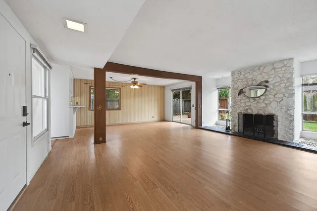 a view of an empty room with wooden floor and a fireplace