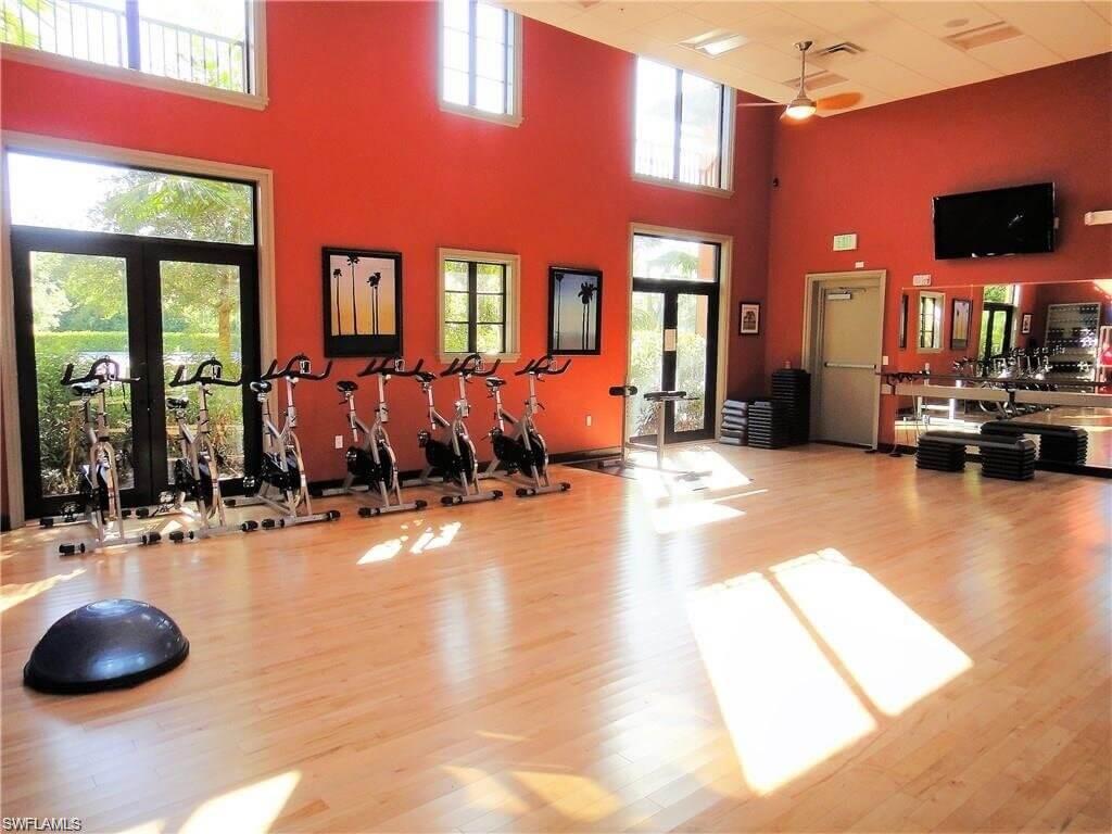 9076 Rialto Street, Unit 6204 Naples, FL 34113 - Photo 43 of 50 Group fitness room featuring light wood-finish flooring, high ceilings, and floor-to-ceiling windows