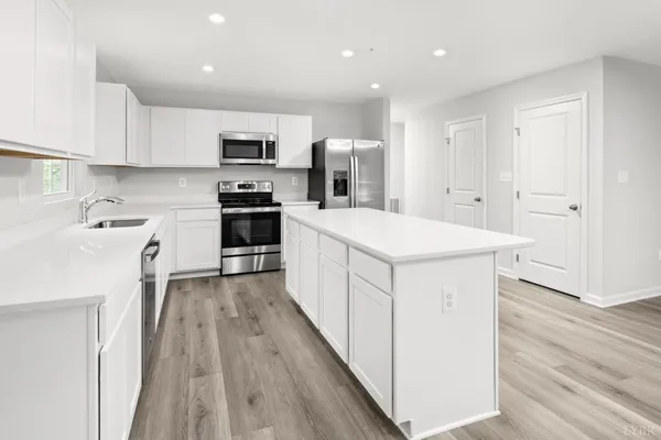 a kitchen with stainless steel appliances kitchen island wooden floors and white cabinets