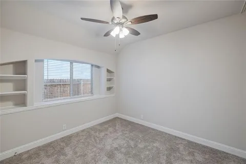 an empty room with a chandelier fan and windows