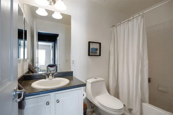 a bathroom with a sink a toilet a mirror and shower curtain