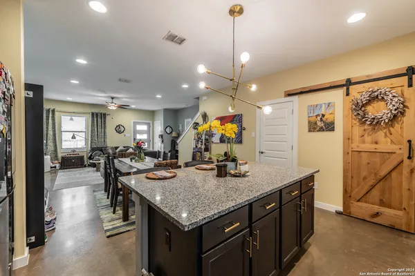 a living room with furniture kitchen view and a chandelier