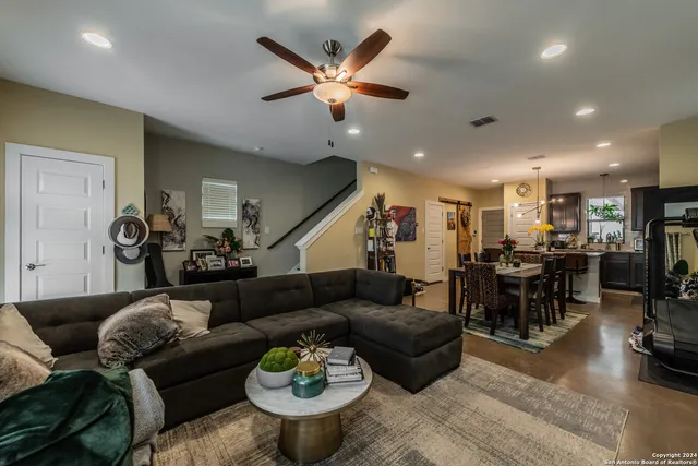 a living room with furniture kitchen view and a chandelier