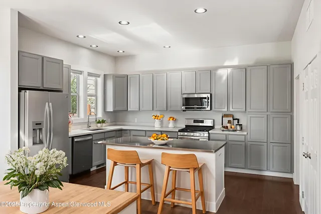 a kitchen with granite countertop a refrigerator stove microwave and sink