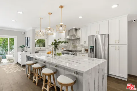 a kitchen with stainless steel appliances a table chairs and wooden floor
