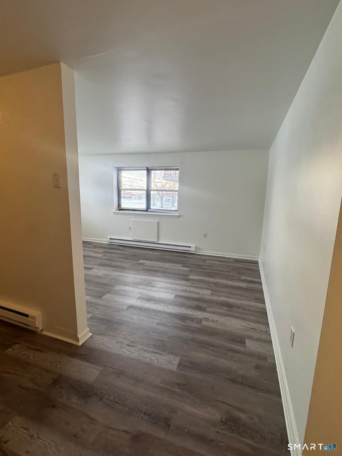 832 Atlantic Street, Unit 2A Bridgeport, CT 06604 - Photo 6 of 11 an empty room with wooden floor and windows