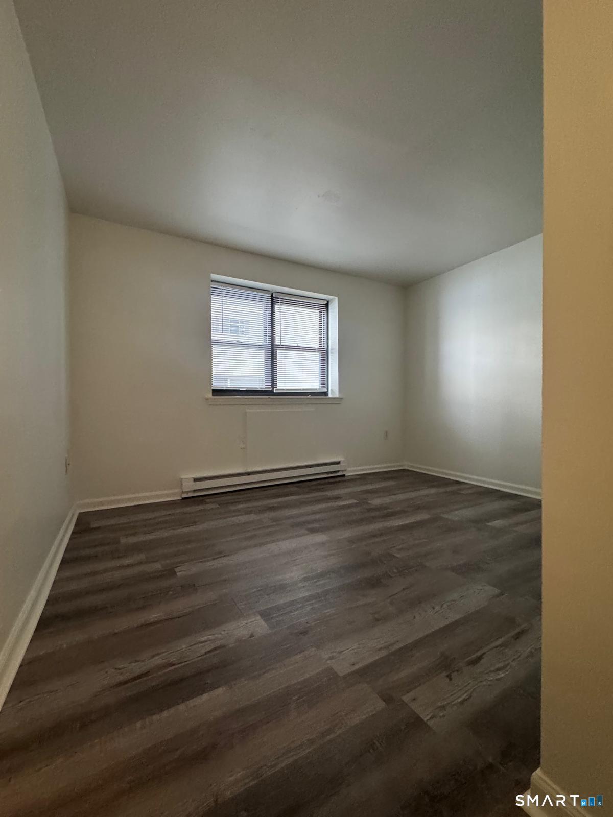 832 Atlantic Street, Unit 2A Bridgeport, CT 06604 - Photo 9 of 11 an empty room with wooden floor and windows