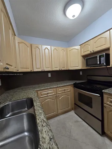 a kitchen with granite countertop a stove sink and cabinets