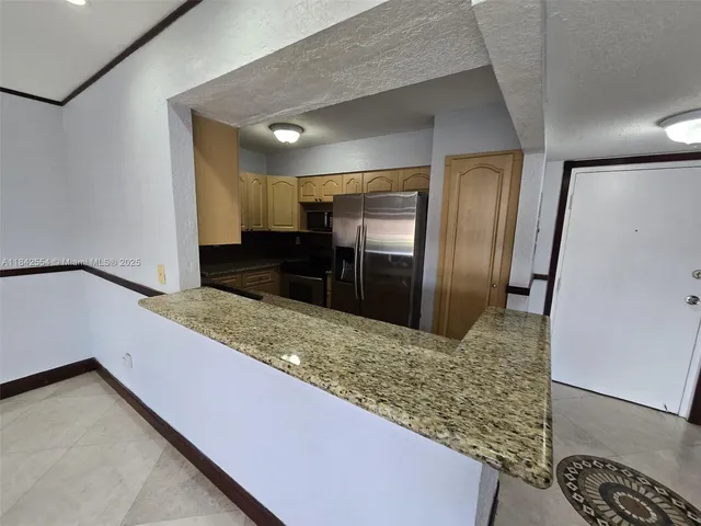 a kitchen with granite countertop a refrigerator and a sink