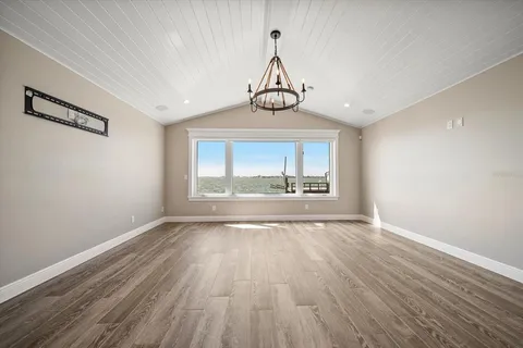 an empty room with wooden floor ceiling fan and windows