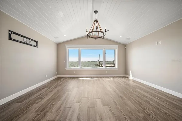 an empty room with wooden floor ceiling fan and windows