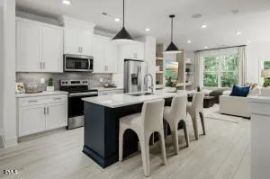a large kitchen with stainless steel appliances kitchen island granite countertop a stove a sink a refrigerator and a dining table with wooden floor