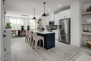 a kitchen with stainless steel appliances a dining table chairs refrigerator and cabinets