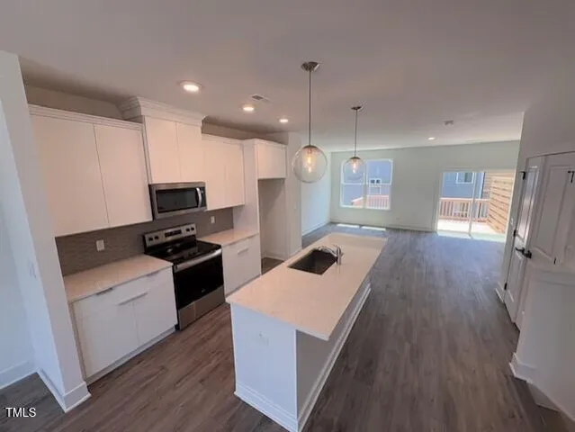 a kitchen with stainless steel appliances kitchen island granite countertop a stove a sink a refrigerator and a microwave