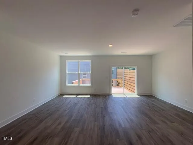 a view of an empty room with wooden floor and window