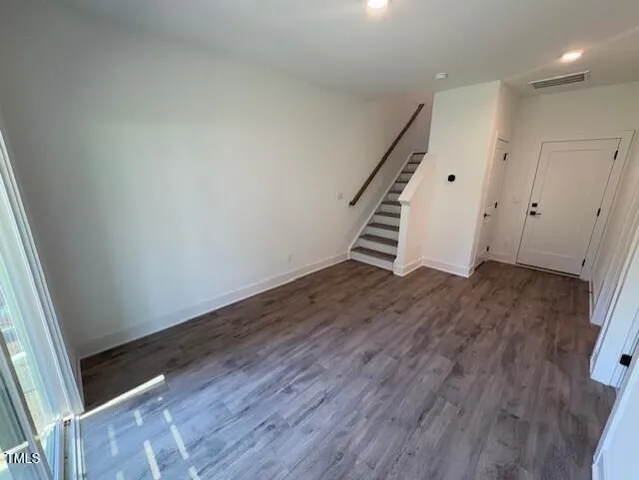 an empty room with wooden floor and staircase