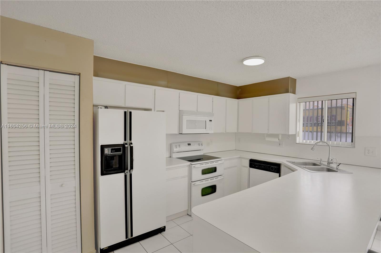 3131 West 79th Place Hialeah, FL 33018 - Photo 9 of 38 a kitchen with a sink a refrigerator and cabinets