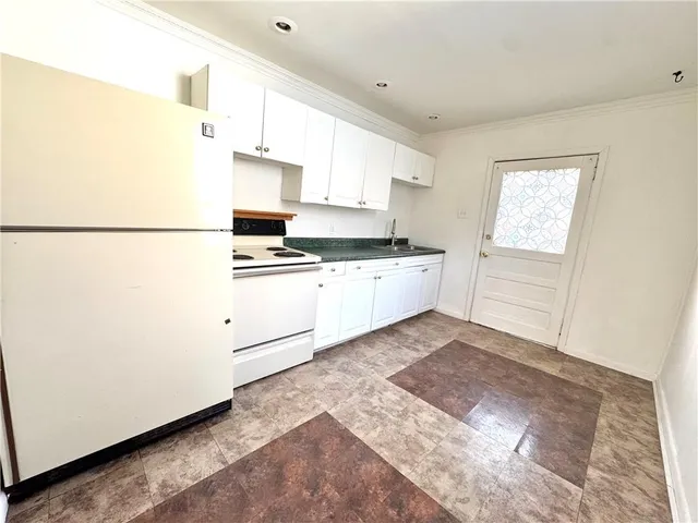 a kitchen with granite countertop a refrigerator sink stove and cabinets