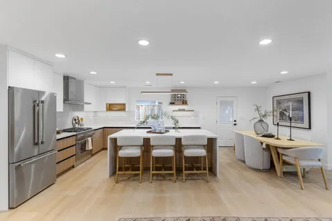 a kitchen with kitchen island a dining table and chairs