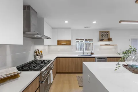 a kitchen with stainless steel appliances a sink a stove top oven a counter space and cabinets