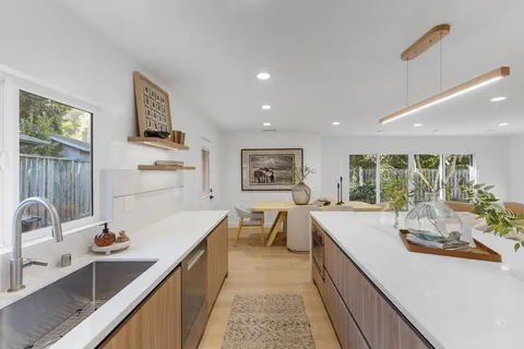 a view of a kitchen with kitchen island a sink appliances wooden floor and a counter top space