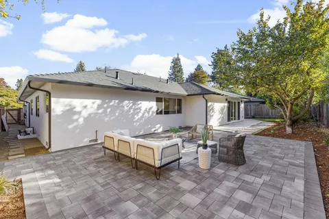 a view of a backyard with table and chairs potted plants and wooden fence