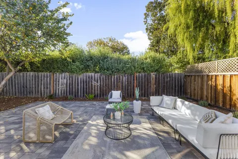 a view of a backyard with large trees and wooden fence