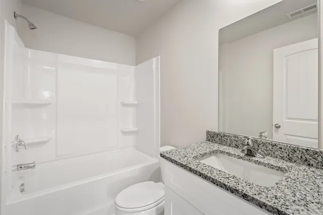 a bathroom with a granite countertop sink a toilet and bathtub