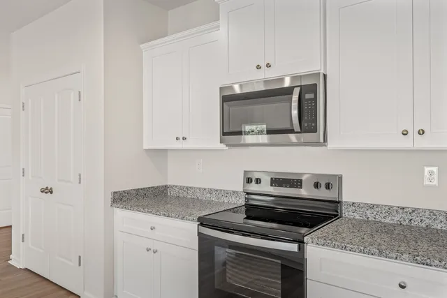 a kitchen with granite countertop a stove top oven microwave and cabinets