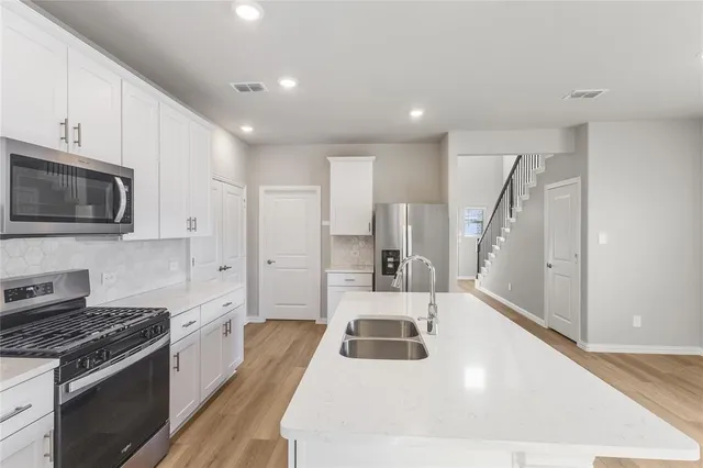 a kitchen with stainless steel appliances a stove a sink and a microwave