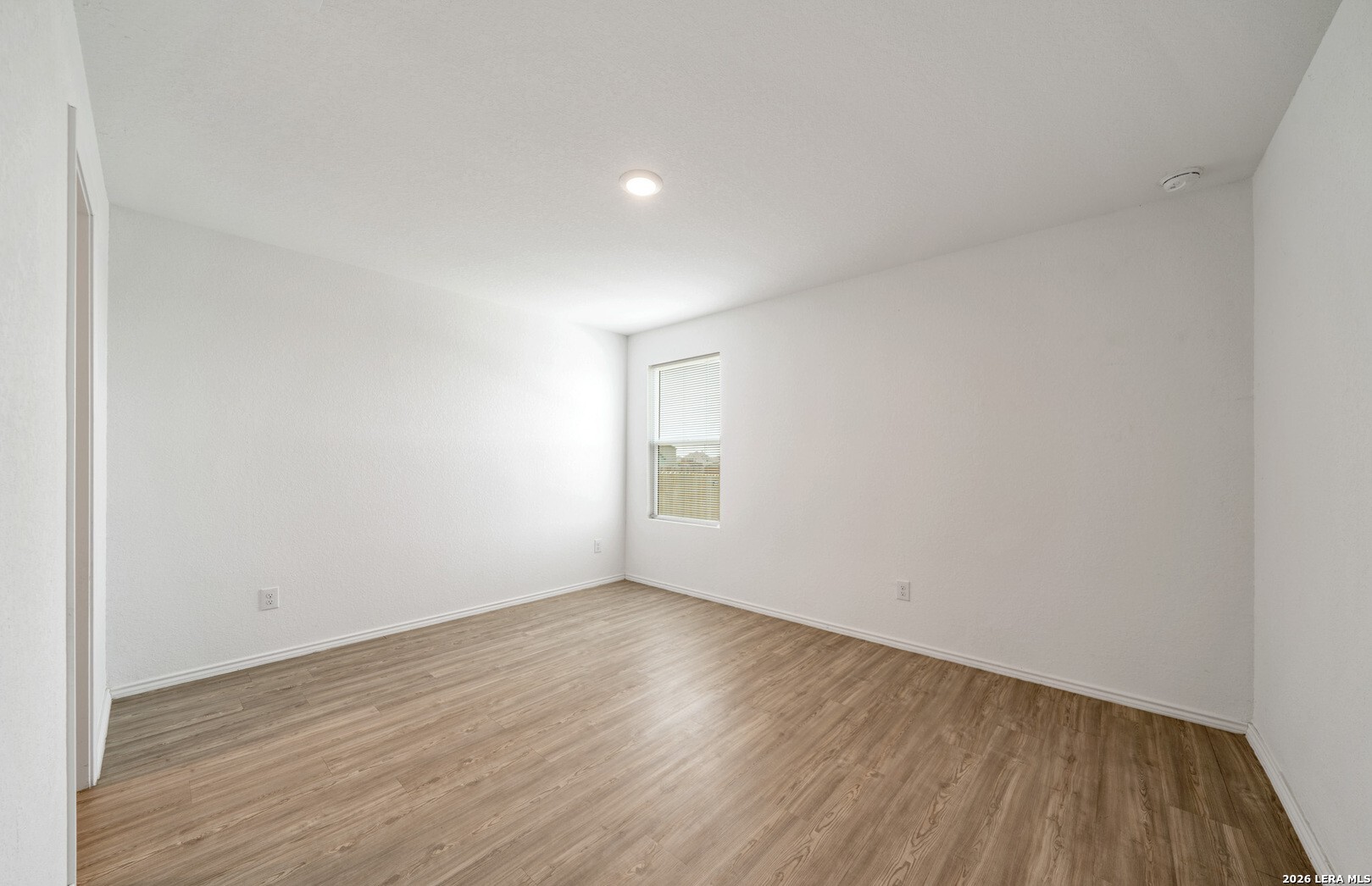 6566 Runaway Row Converse, TX 78109 - Photo 13 of 27 a view of an empty room with wooden floor and a window