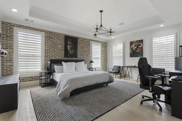 a spacious bedroom with a bed a desk and chair with window