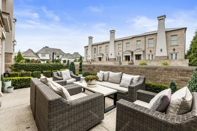 a view of a patio with couches chairs potted plants and wooden fence