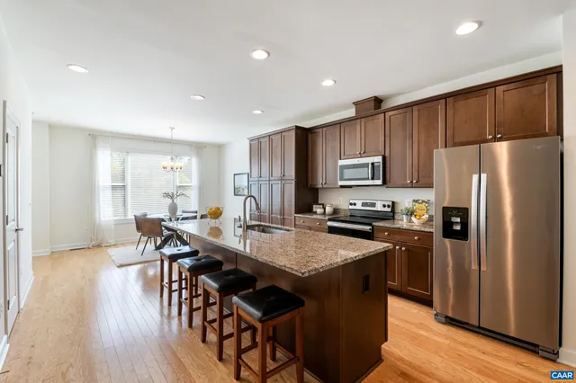 a kitchen with granite countertop a table chairs microwave and refrigerator