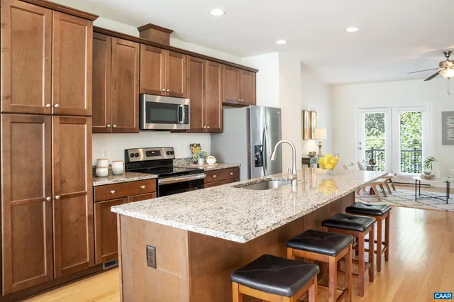 a kitchen with kitchen island granite countertop a refrigerator a stove and a sink with wooden floor