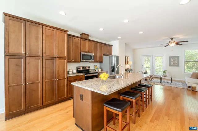 a kitchen with stainless steel appliances granite countertop a refrigerator a sink dishwasher and a stove with wooden floor