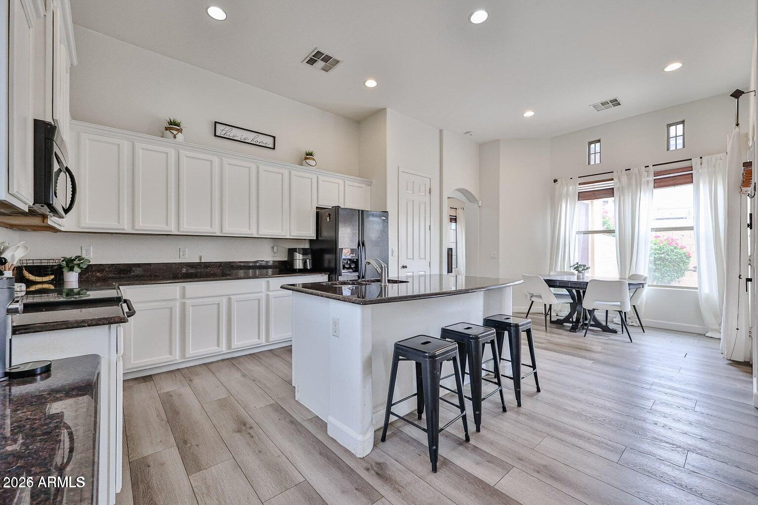 3950 North Edith Way Buckeye, AZ 85396 - Photo 10 of 32 a kitchen with white cabinets stainless steel appliances and dining table