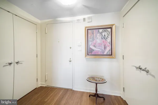 a living room with couches a coffee table and kitchen view with wooden floor